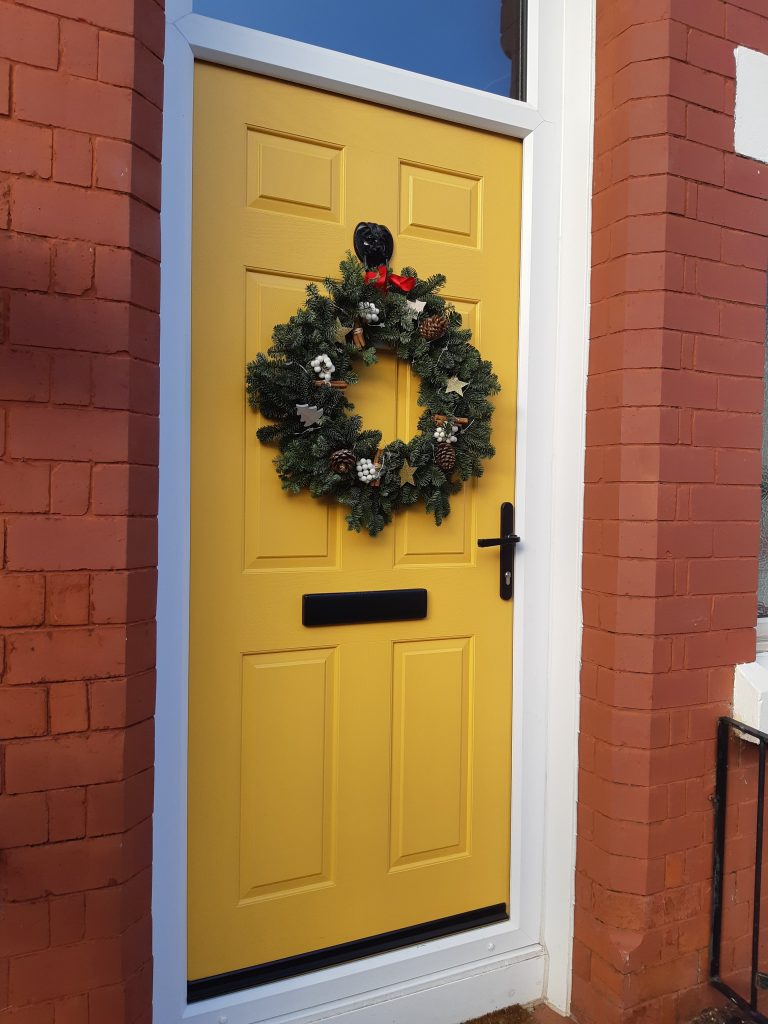 Yellow composite door with christmas wreath