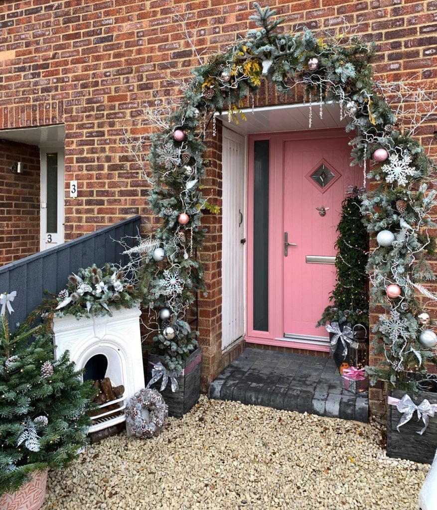 Pink front door with sidelight adorned with christmas decorations