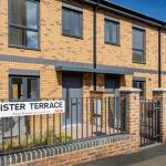 Newly built terraced housing at Lister Terrace in the Royal Borough of Greenwich, featuring a sleek gray XtremeDoor composite door. The door's contemporary design contrasts well with the warm brickwork, complementing the modern aesthetic of the development.