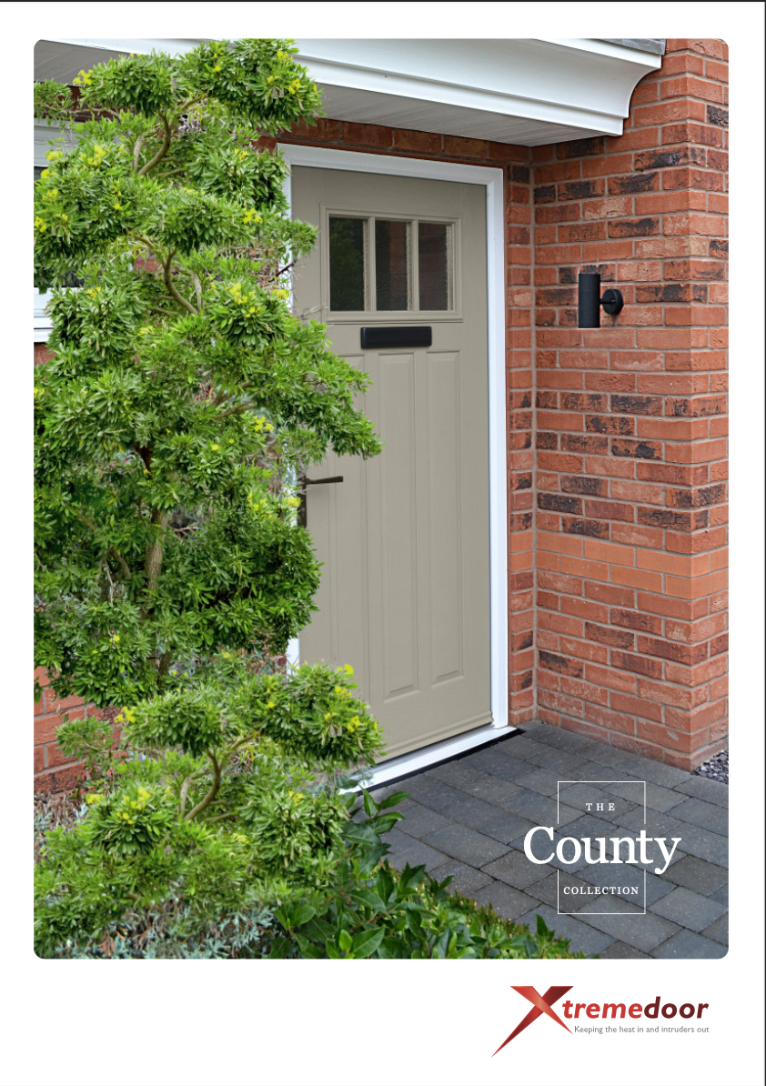 This brochure image presents 'The County Collection' from XtremeDoor. It features a taupe-coloured composite door installed in a home setting, with a white frame and a rectangular glazed panel at the top. The door is accessorised with a black letterbox and a stylish black handle. To the left of the door is a lush green shrub, and to the right, the door is flanked by red brickwork and an outdoor wall lantern. The doorstep is paved with grey stone tiles. The XtremeDoor logo is at the bottom with the tagline 'Keeping the heat in and intruders out', signifying the brand's focus on thermal efficiency and security