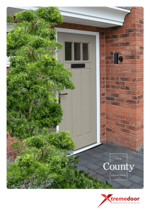 This brochure image presents 'The County Collection' from XtremeDoor. It features a taupe-coloured composite door installed in a home setting, with a white frame and a rectangular glazed panel at the top. The door is accessorised with a black letterbox and a stylish black handle. To the left of the door is a lush green shrub, and to the right, the door is flanked by red brickwork and an outdoor wall lantern. The doorstep is paved with grey stone tiles. The XtremeDoor logo is at the bottom with the tagline 'Keeping the heat in and intruders out', signifying the brand's focus on thermal efficiency and security